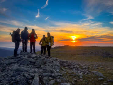 A group of mountaineers at sunset on the Carneddau in Eryri whilst on a Mountain Leader course with Beyond the Edge.