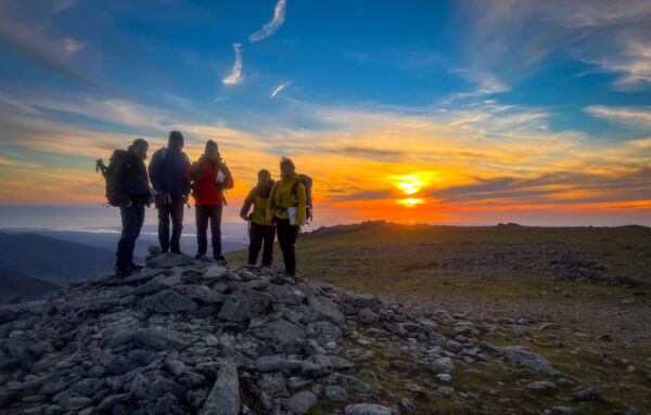 A group of mountaineers at sunset on the Carneddau in Eryri whilst on a Mountain Leader course with Beyond the Edge.