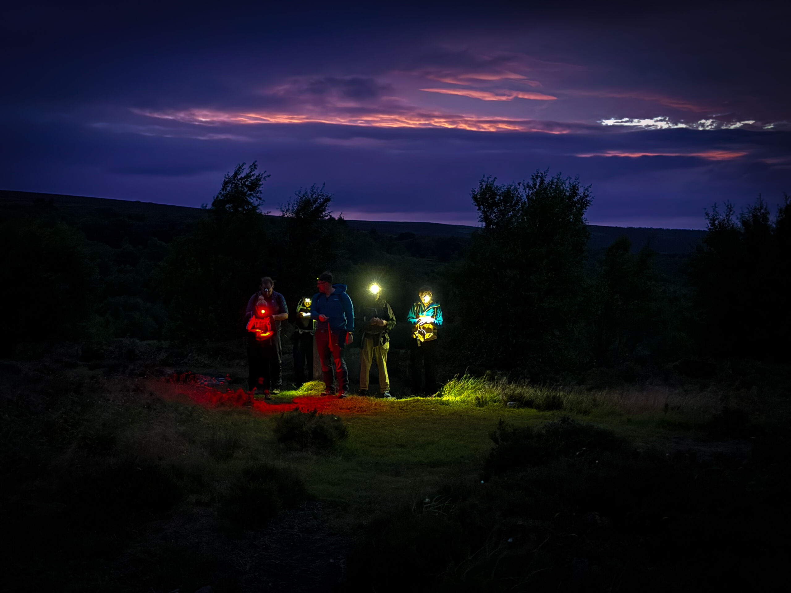 A group learning night navigation techniques on a Hill and Moorland Leader course in the Peak District.