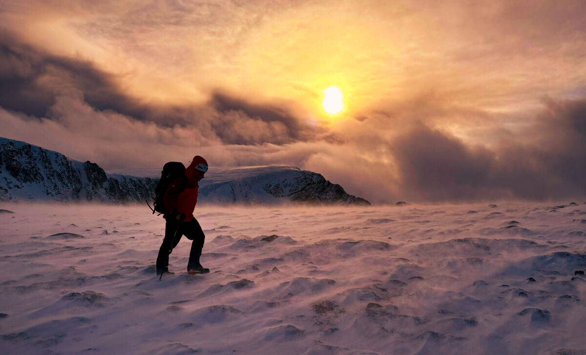 A man walks in a winter storm on Cairngorm whilst on an Introduction to Winter mountaineering course.