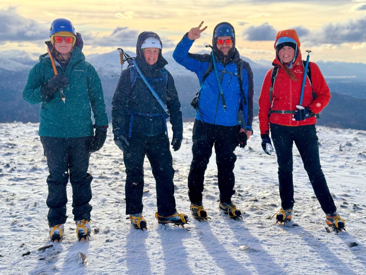 A group on top of a mountain in a snow storm whilst on an Introduction to Winter Mountaineering course.
