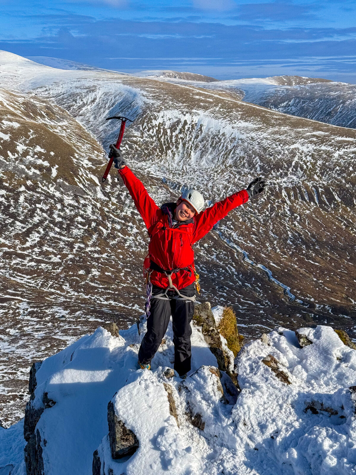 A lady celebrates a successful winter mountaineering ascent of Beinn a Chaoriann.