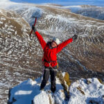 A lady celebrates a successful winter mountaineering ascent of Beinn a Chaoriann.