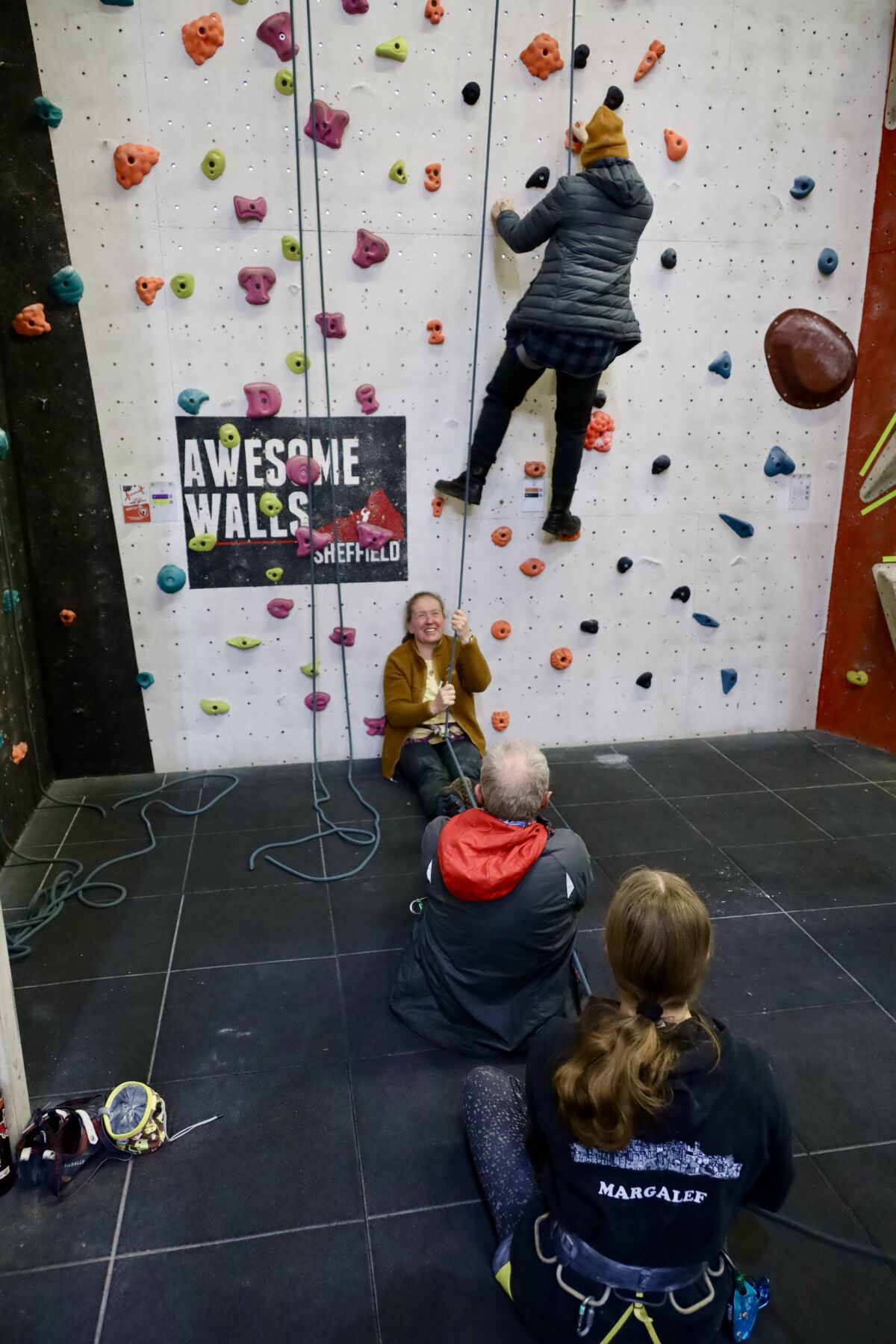 A group practicing bell ringing on a Climbing wall Instructor course.