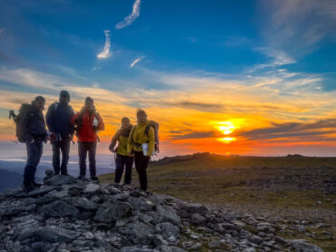 A Mountain Leader training group standing on the Carneddau in Wales at sunset.