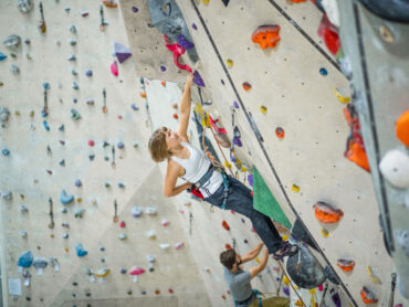 A young lady lead climbing preparing for a Climbing wall Development Instructor course