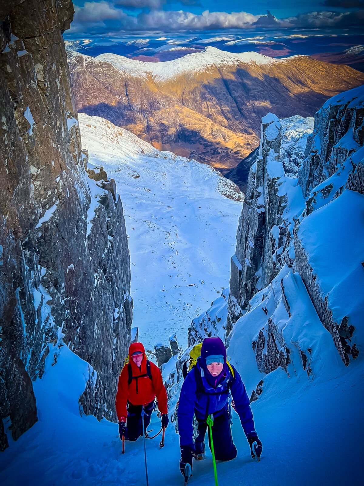 A lady and man climb steep snow on a winter mountaineering course.