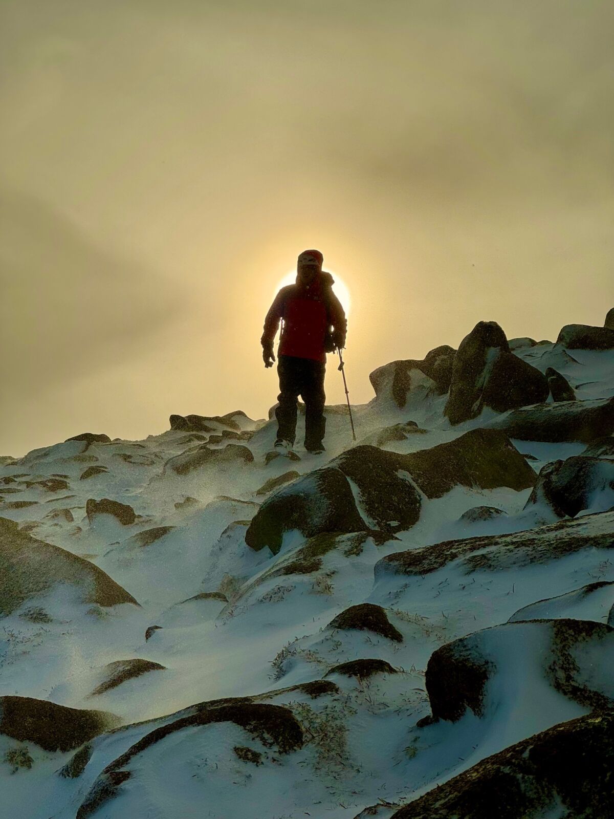 A man in a winter storm walks off a mountain on a guided winter walking course.