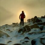 A man in a winter storm walks off a mountain on a guided winter walking course.