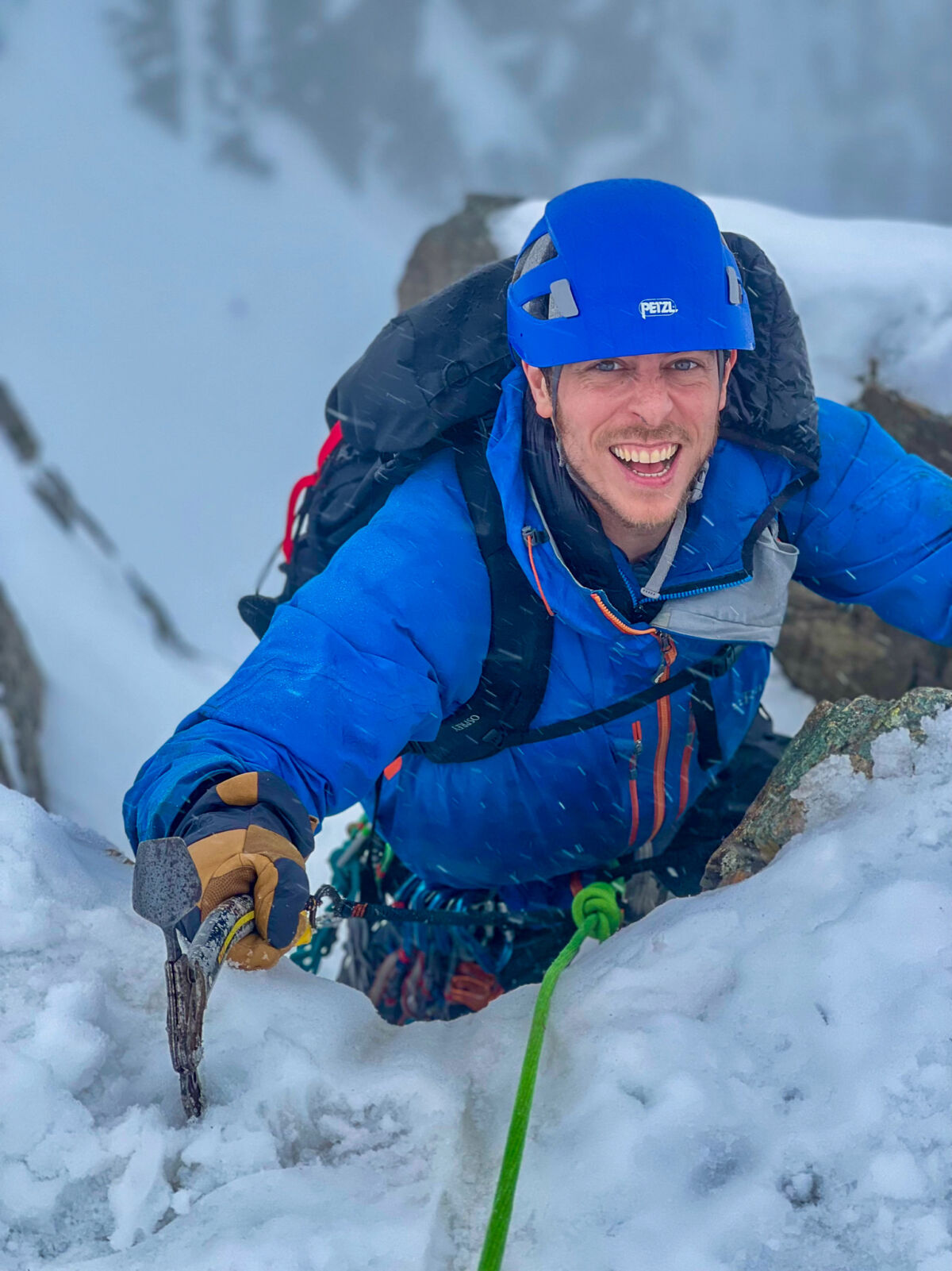 A man with an ice axe climbing snow and ice on a winter mountaineering course in Scotland.