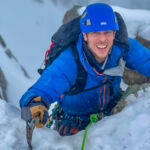 A man with an ice axe climbing snow and ice on a winter mountaineering course in Scotland.