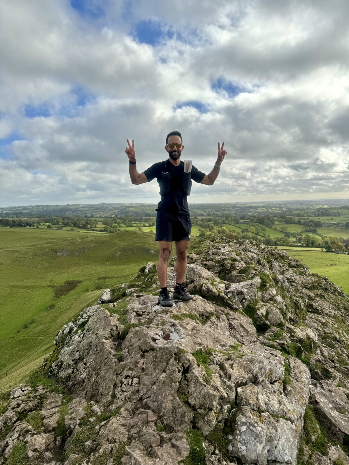 A man stands on top of Thorpe Cloud whilst on a Trail running course in the Peak District.
