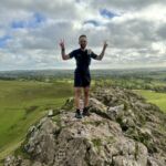 A man stands on top of Thorpe Cloud whilst on a Trail running course in the Peak District.