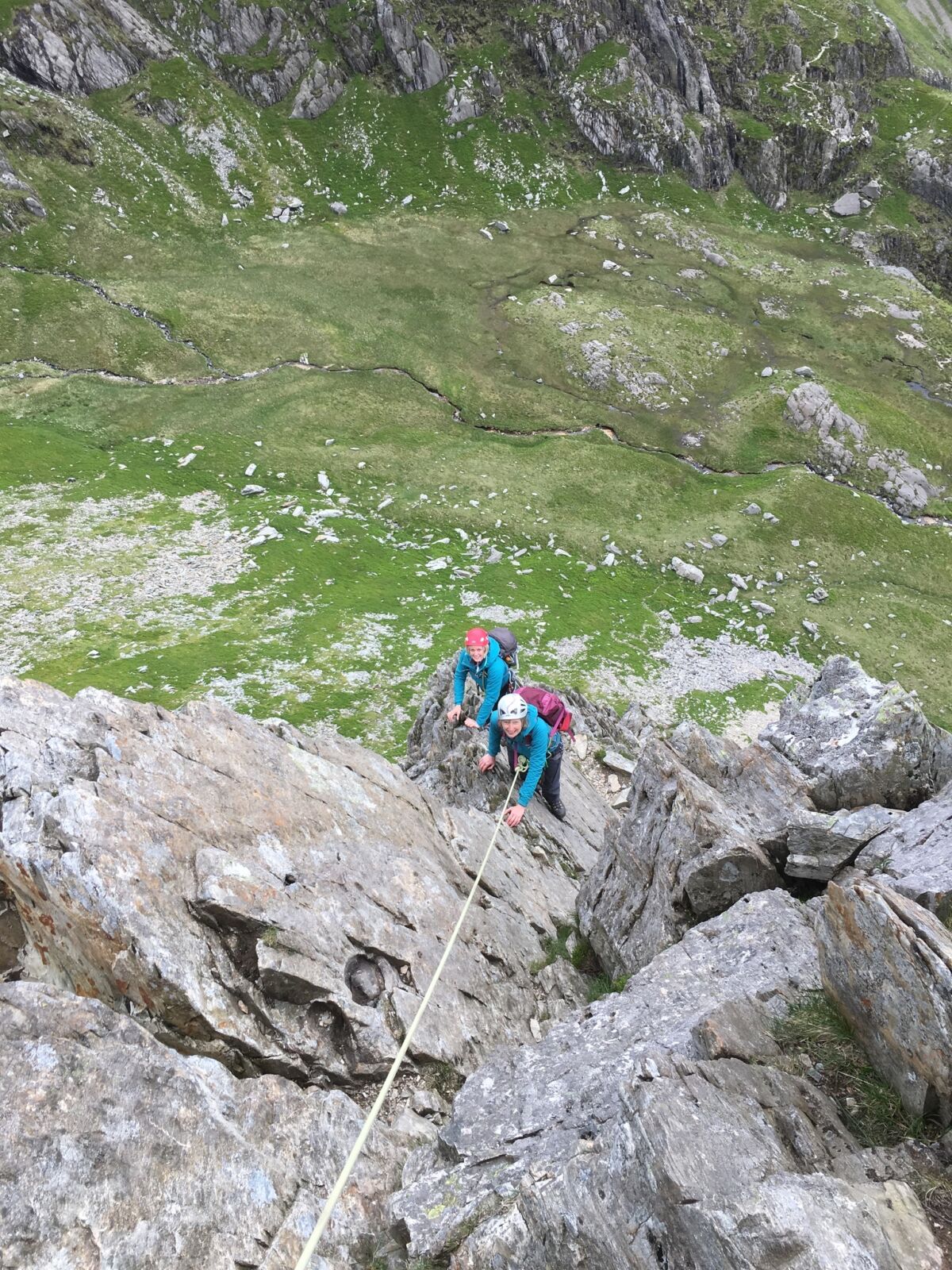 Two women on a rope with a big drop below them whilst on an Advanced Scrambling course in Eryri, N Wales.