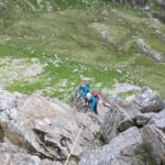 Two women on a rope with a big drop below them whilst on an Advanced Scrambling course in Eryri, N Wales.