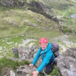 A woman smiling whilst scrambling up Cneifon Arete on an Advanced Scrambling course.