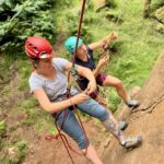Two women climbers on a climbers self rescue course half way up a cliff in the Peak District.