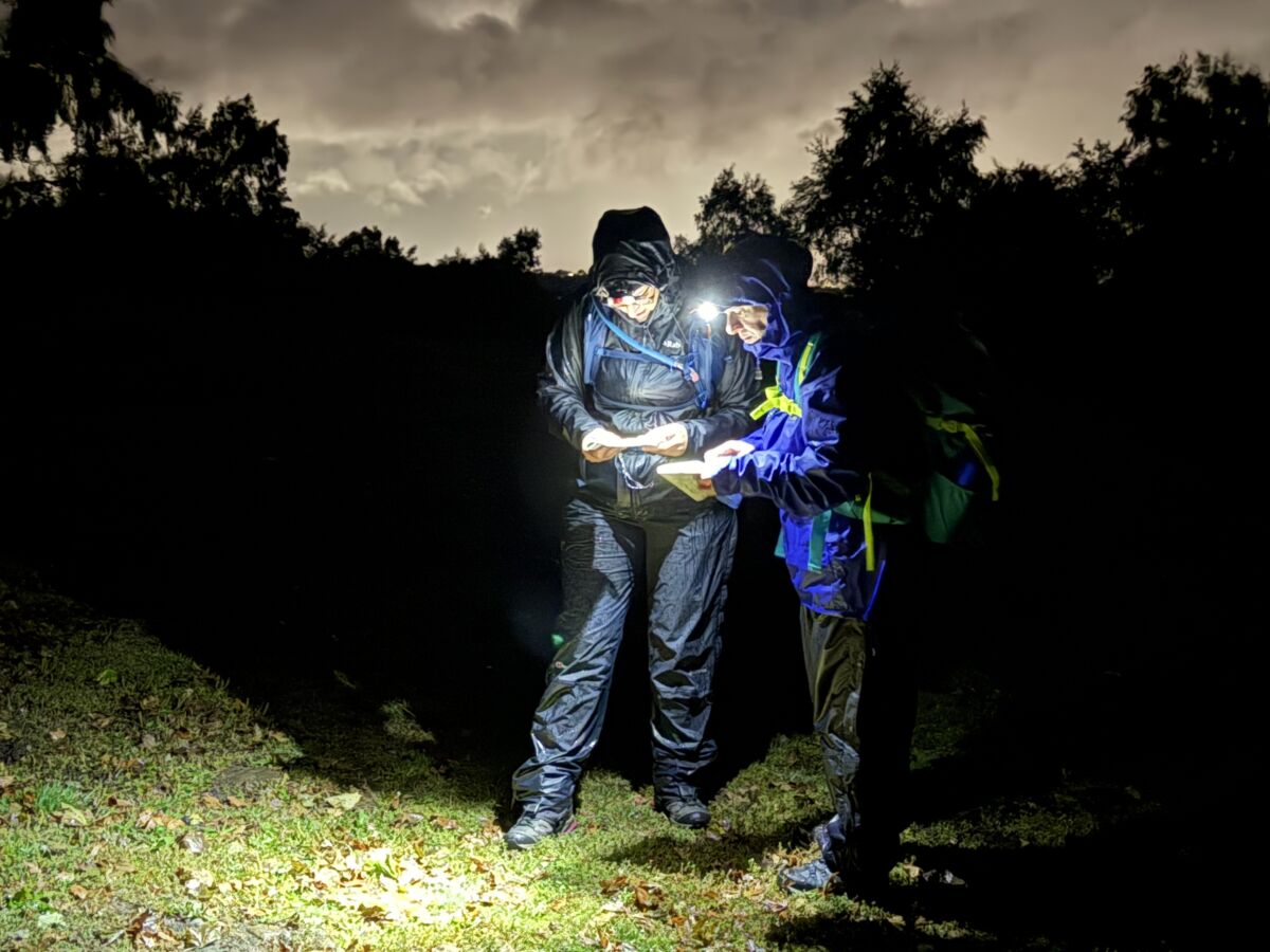 Two ladies navigating with a map and compass in the dark on a Hill and Moorland leader course in the peak District.