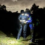 Two ladies navigating with a map and compass in the dark on a Hill and Moorland leader course in the peak District.