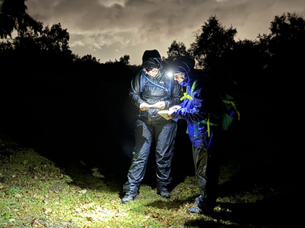 Two ladies navigating with a map and compass in the dark on a Hill and Moorland leader course in the peak District.