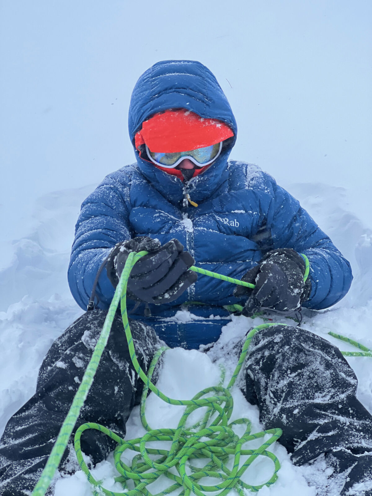 A lady learning to waist belay in the snow on a winter mountaineering course