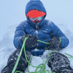 A lady learning to waist belay in the snow on a winter mountaineering course