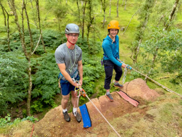 Two rock climbers abseiling over an edge in the Peak District practicing self rescue techniques.