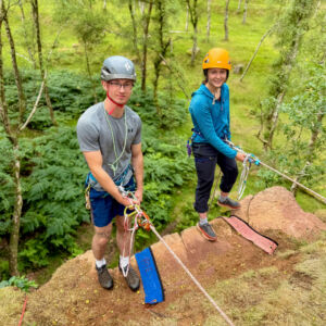 Two rock climbers abseiling over an edge in the Peak District practicing self rescue techniques.