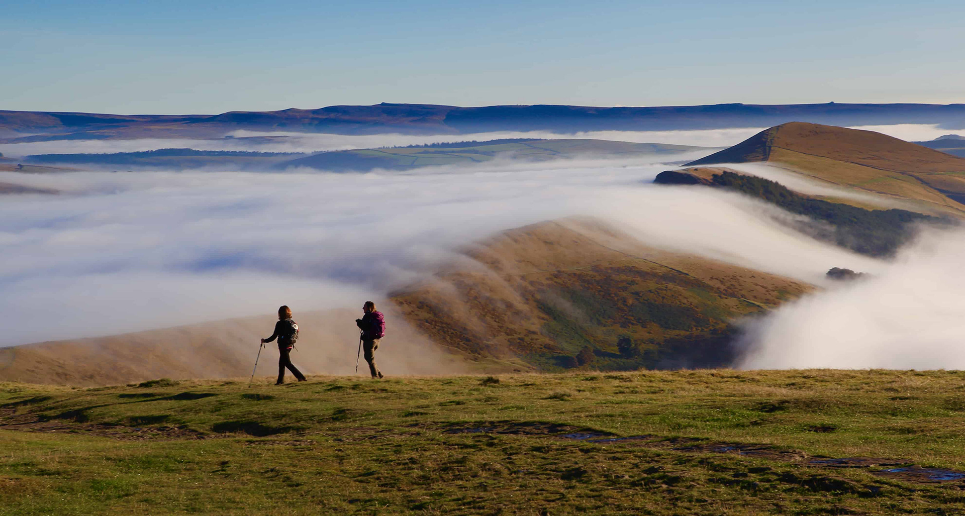 Hillwalking in the Peak District. Two walkers descend off Mam Tor heading to Lose hill.