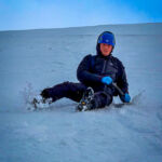 A man using an ice axe to self arrest on a winter skills course in Aviemore, Scotland.
