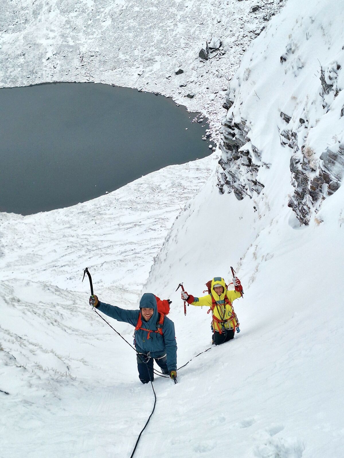 Two climbers climbing a gully in Scotland on a winter climbing course.