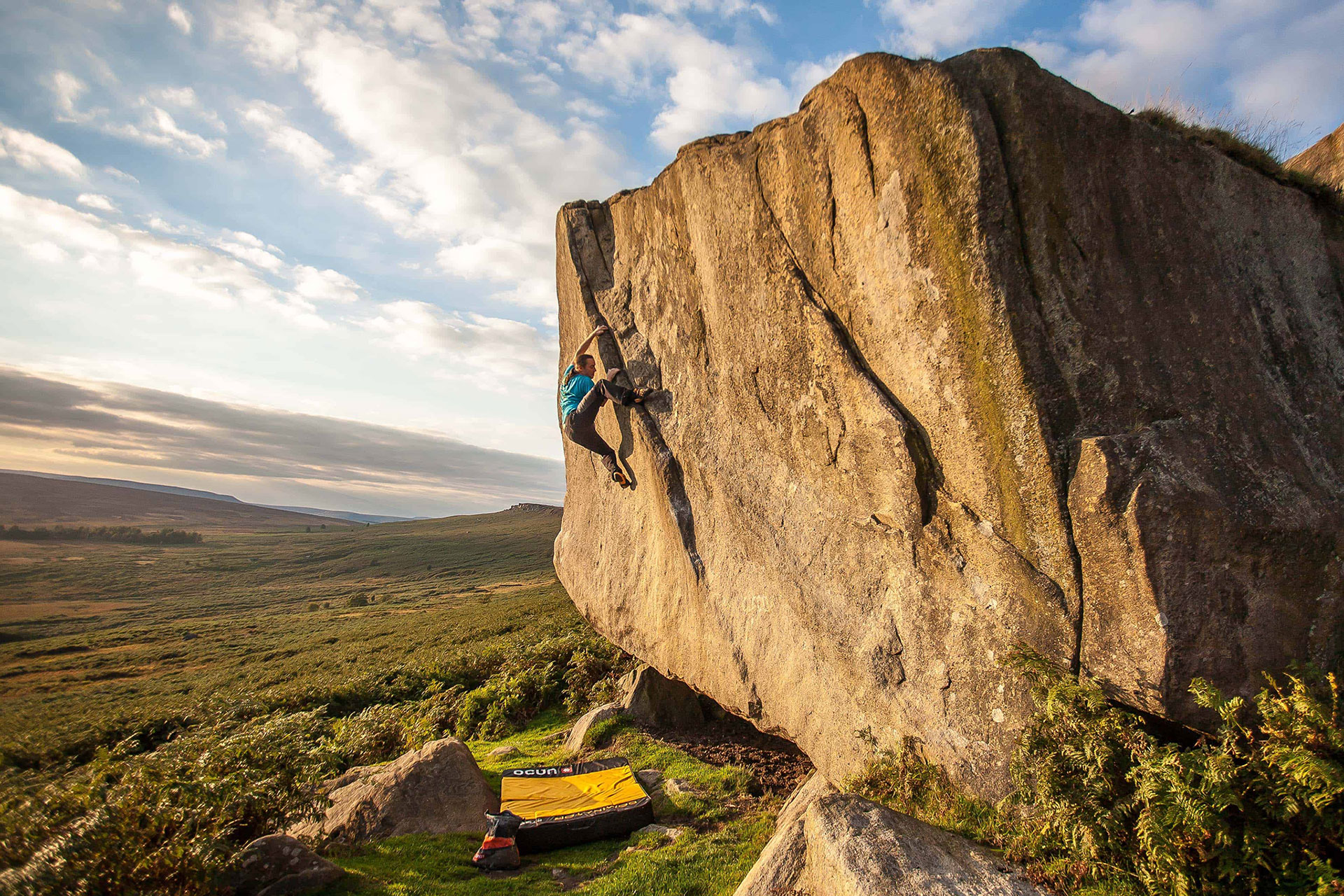 A man bouldering at Stanage Edge in the Peak District.