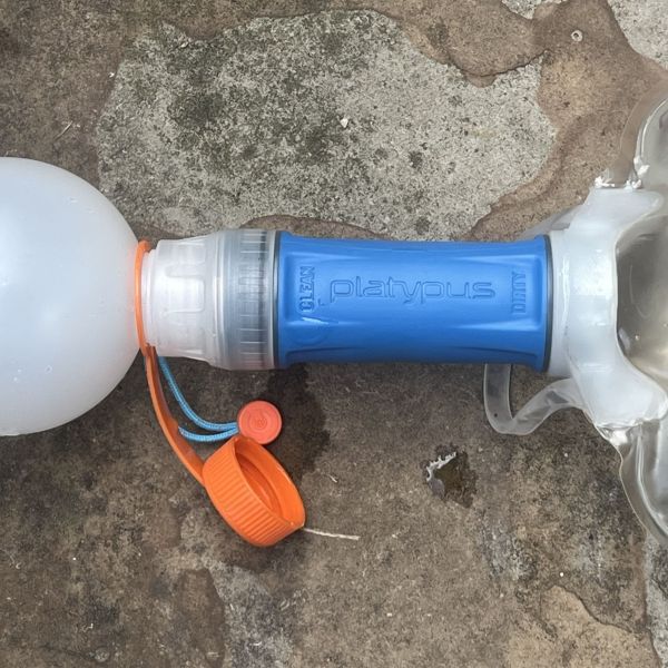 A blue Platypus Quickdraw water filter on stone