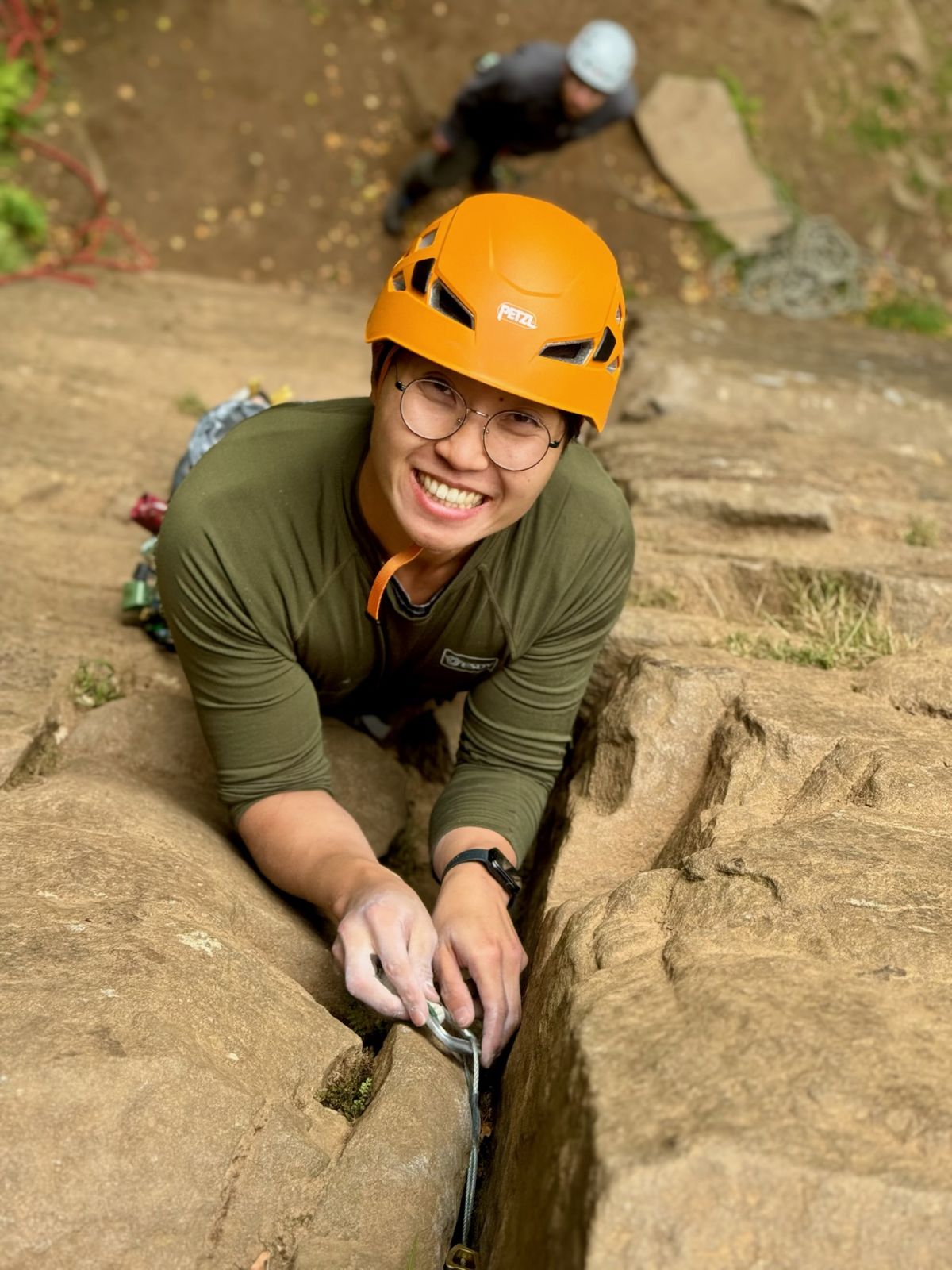 A man reaches the top of a rock climb, whilst learning to lead climb on a Beyond the Edge course in the Peak District.