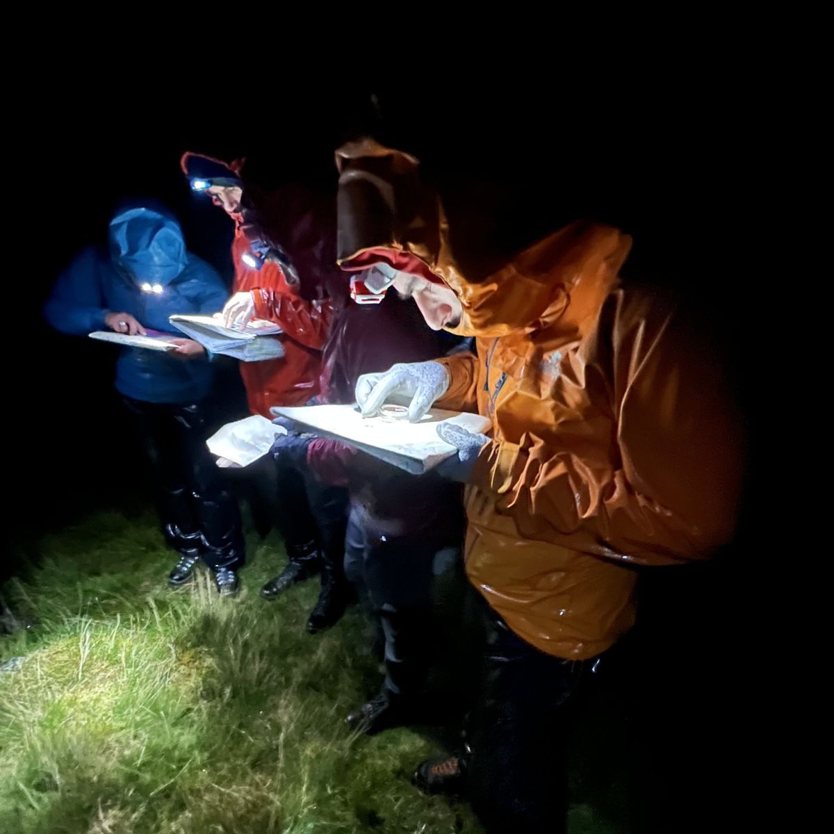 Two people navigating and map reading at night wearing a head torch